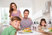 stock photo of time  - Family looking at the camera at dinner time in kitchen - JPG 