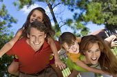 pic of family  - An attractive happy smiling family of mother father son and daughter having fun outside in a park in warm summer sunshine - JPG 