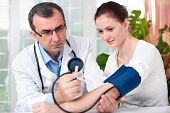 stock photo of pressure  - Male doctor checking young woman blood pressure - JPG 