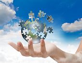 stock photo of globe  - Business concept with a hand building puzzle globe - JPG 