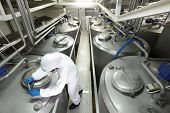 stock photo of industrial  - technician in white protective uniform and goggles closing industrial process tank in plant - JPG 