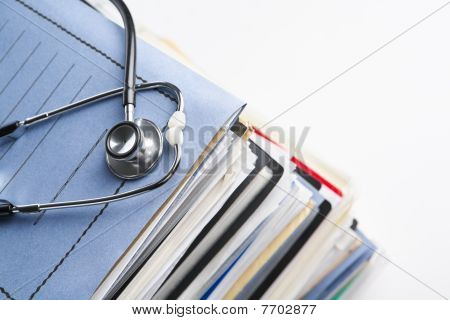 Picture or Photo of Medical record concept with stetoschope over pile of document. Selective focus on the front side of the stethoscope