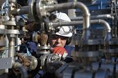 stock photo of industrial  - engineer standing behind pipeline machinery inside oil refinery - JPG 