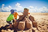 foto of buildings  - Two little boys building large sandcastle on the beach - JPG 