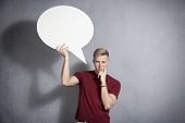 foto of informative  - Questioning man  holding white blank speech bubble with space for text isolated on grey background - JPG 