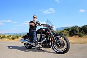 foto of transportation  - A young biker riding a customized motorcycle on an open road - JPG 