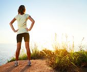 pic of sunset  - Young slim lady worn training clothes standing on countryside path and enjoying sunset - JPG 