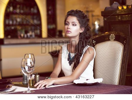 Picture or Photo of Dating. Dreaming Woman waiting at Decorated Table in Restaurant Interior