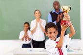 pic of education  - happy male elementary school student holding a trophy in classroom - JPG 