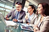 picture of meeting  - Portrait of business partners pointing and looking at laptop display at meeting - JPG 