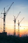 stock photo of industrial  - Industrial construction cranes  silhouettes on sunset - JPG 