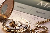 stock photo of watch  - Close up of a gold pocket watch on calendar - JPG 