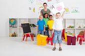 foto of preschool  - happy preschool boy showing his artwork in classroom - JPG 