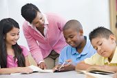 stock photo of student  - Students in class reading with teacher helping  - JPG 