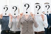pic of team  - Business team hiding their faces behind question mark signs at office - JPG 