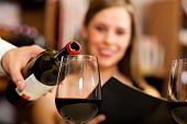 stock photo of pour  - Waiter pouring red wine to a woman - JPG 