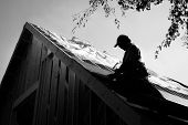 stock photo of construction worker  - black and white of man installing roof with hammer
 - JPG 