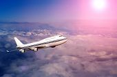 image of transportation  - passenger airplane in the clouds at sunset or dawn - JPG 