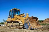pic of construction  - Yellow bulldozer at a construction site against blue sky - JPG 
