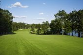 image of golf  - Beautiful golf fairway lined with trees alongside a lake leading to green - JPG 