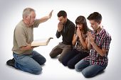 stock photo of young adult  - Preacher leading three young souls in prayer to receive Jesus - JPG 