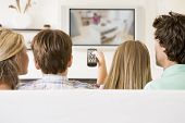 stock photo of family  - Families sat on sofa at home watching tv - JPG 