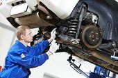 stock photo of failure  - car mechanic inspecting car wheel and suspension detail of lifted automobile at repair service station - JPG 