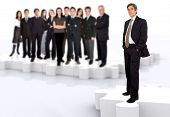 image of leadership  - business leadership and teamwork with a businessman in front of a businessteam all standing on puzzle pieces - JPG 