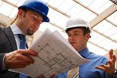 pic of construction  - Two construction workers in hardhats looking at blueprints - JPG 