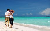 stock photo of beach  - Young loving couple walking along tropical white sand beach - JPG 