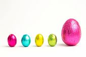 pic of wrapped  - Four small easter eggs beside large one wrapped in colourful foil on white background - JPG 