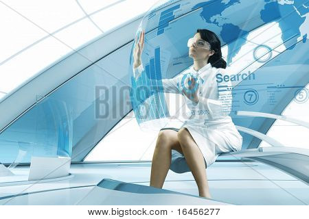 Picture or Photo of Sexy brunette operating transparent future touch interface. Sits in the air chair. Impressive specially designed for this series abstract bio interior. Interfaces collection.