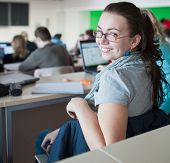 foto of college  - young pretty female college student sitting in a classroom full of students during class - JPG 