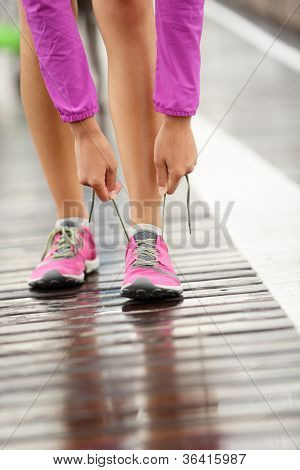 Picture or Photo of Running shoes. Barefoot running shoes closeup. Woman tying laces before jogging in minimalistic barefoot running shoes on Brooklyn Bridge, New York, USA.