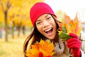 foto of excitement  - Excited happy fall woman smiling joyful and blissful holding autumn leaves outside in colorful fall forest - JPG 