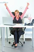 foto of excitement  - Excited modern business woman sitting at office desk and rejoicing her success - JPG 