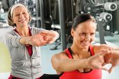 foto of fitness  - Senior woman with personal fitness trainer stretch out at gym - JPG 