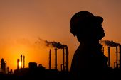 stock photo of sunset  - the silhouette of oil refinery worker at sunset - JPG 