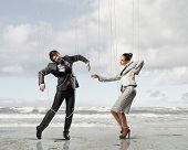 image of businesspeople  - Image of businesspeople hanging on strings like marionettes against sea background - JPG 
