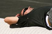 pic of construction worker  - construction worker taking a rest by lying down on a roll of carpeting
 - JPG 