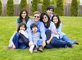 picture of cerebral  - Large multiracial family of seven sitting together on lawn dressed in blue colors - JPG 