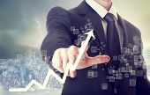 pic of business concept  - Businessman Touching a Graph Indicating Growth on City Background - JPG 