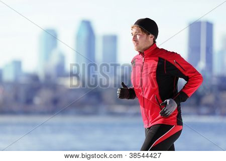 Picture or Photo of Athlete man running sport. Runner in winter jogging outdoors with city skyline in background. Male fitness model in Montreal, Canada.