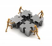 stock photo of teamwork  - Wooden mannequins pushing puzzle pieces into the right place - JPG 
