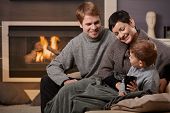 foto of home  - Happy family sitting on couch at home in front of fireplace smiling - JPG 