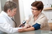 stock photo of pressure  - doctor measuring blood pressure of female patient - JPG 