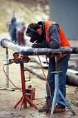 image of construction worker  - construction worker welding pipe  - JPG 