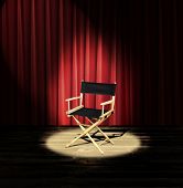 stock photo of spotlight  - A directors chair on a stage with a red curtain and spotlight - JPG 