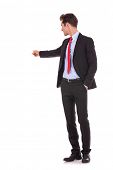 image of points  - young business man pointing at something at his back on white background - JPG 