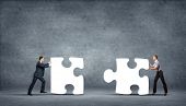 stock photo of business concept  - Team of business people collaborate holding up jigsaw puzzle pieces as a solution to a problem - JPG 